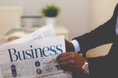 the arms of a man holding a newspaper that says 