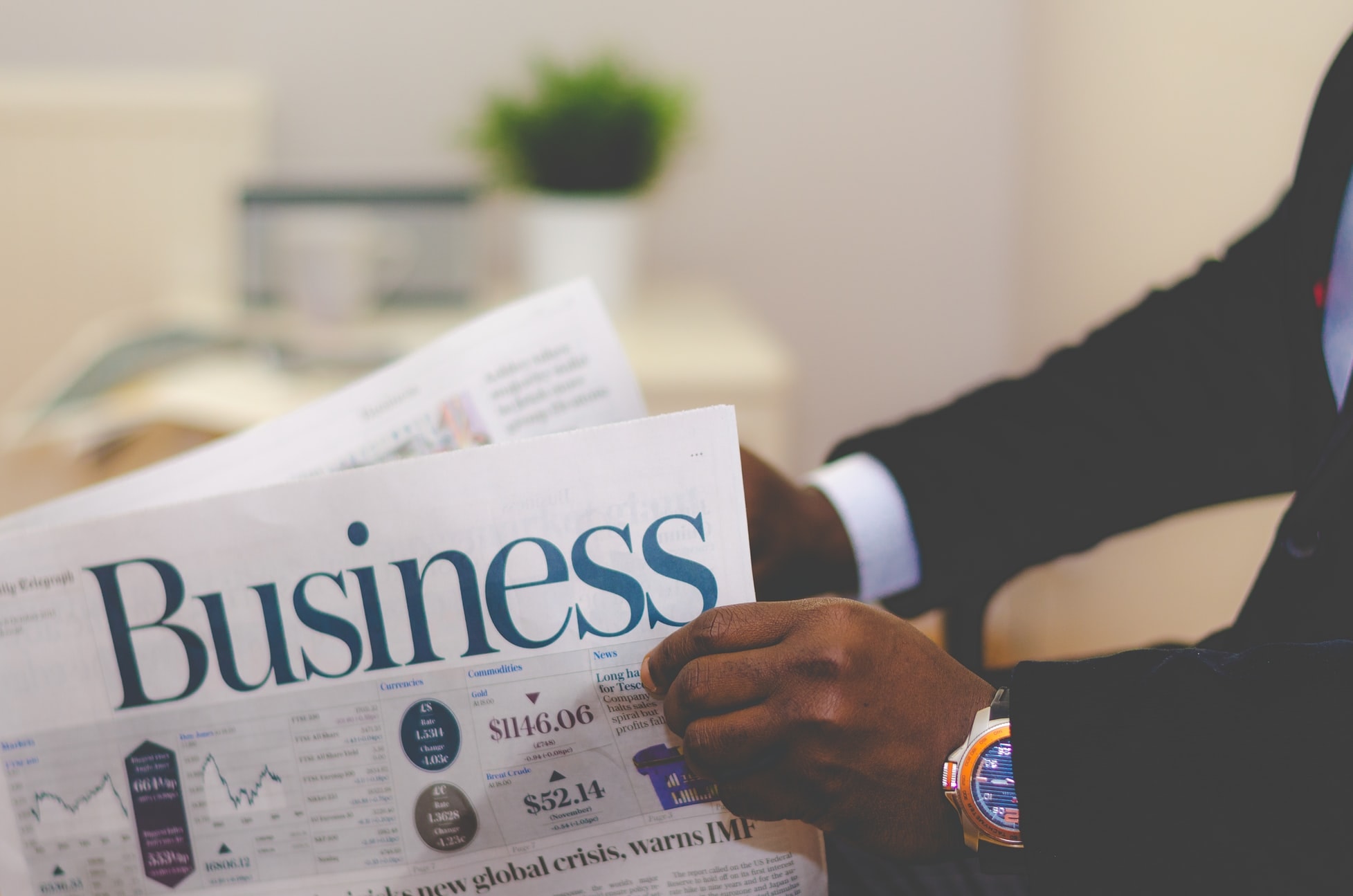 the arms of a man holding a newspaper that says "business"