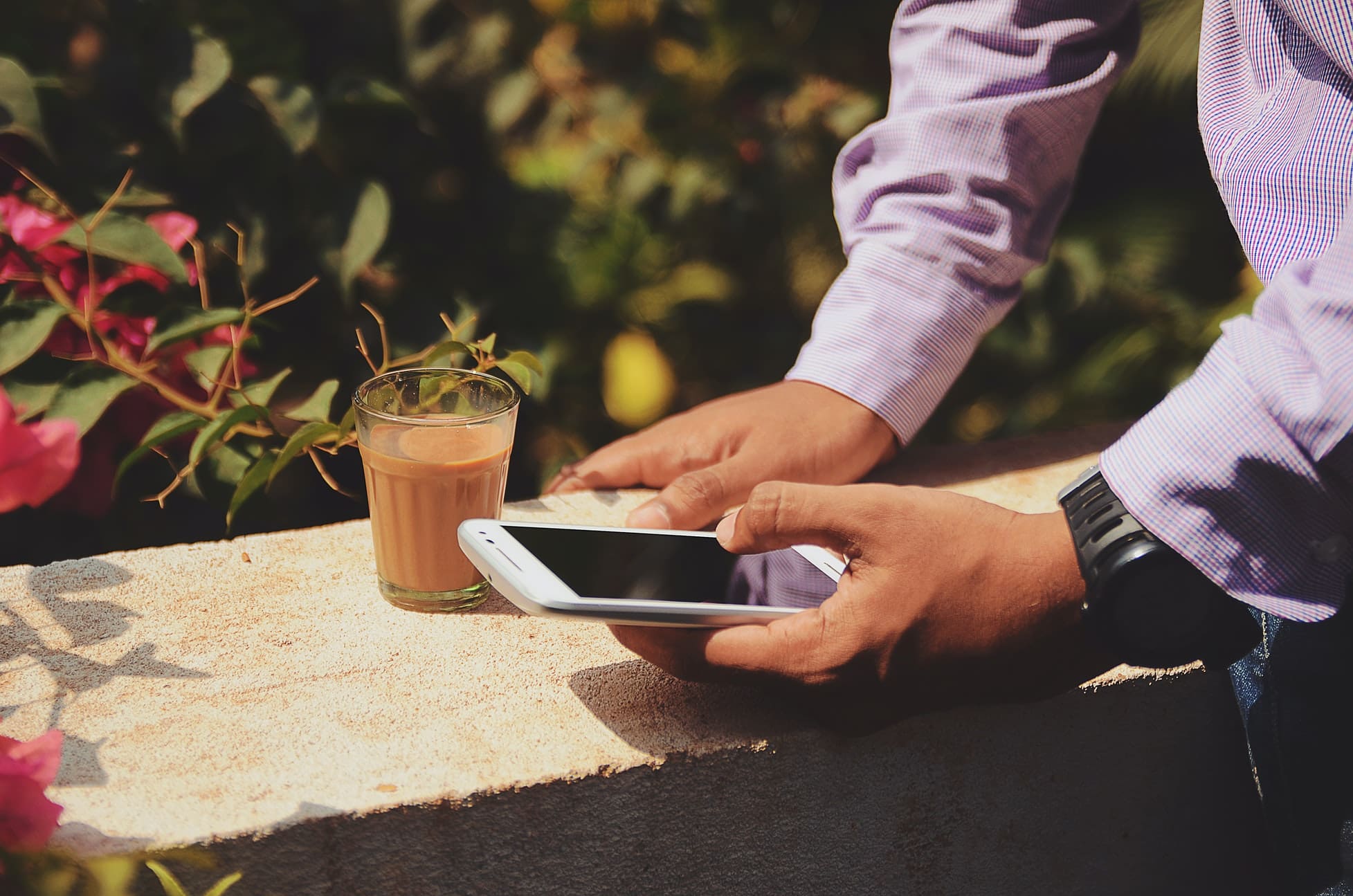 the arms of a man holding a phone outside in sunshine