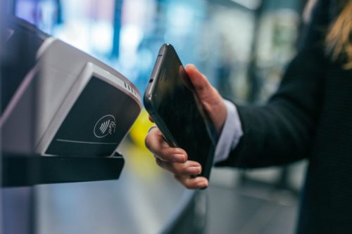 man swiping phone on payment terminal
