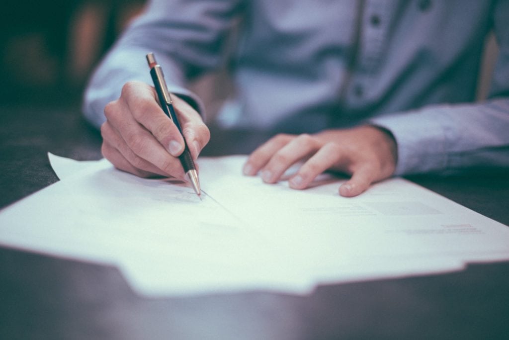 man writing on papers